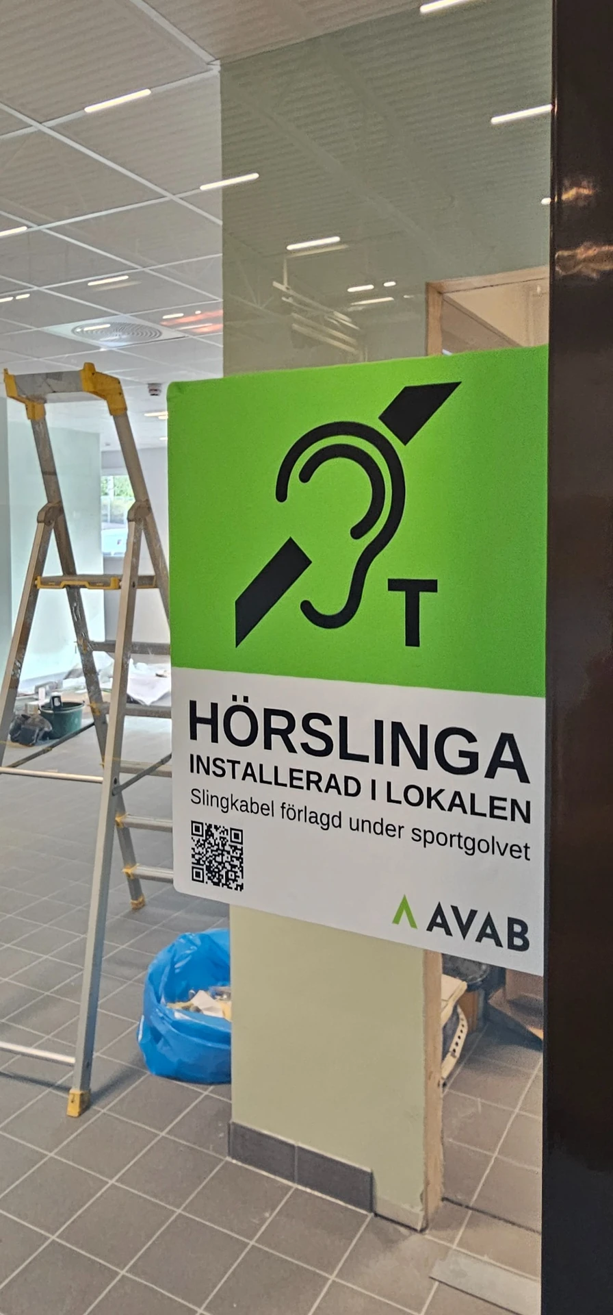 Skylt som visar att hörslinga finns installerad under sportgolvet i Mullhyttans sporthall
